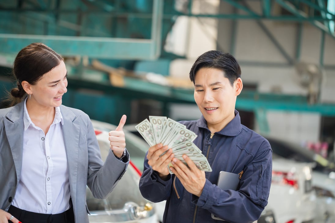 Female customers paying mechanics with cash at the repair garage